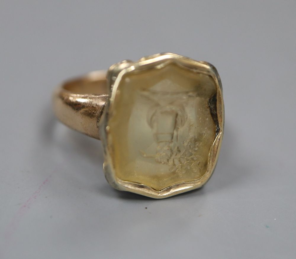A Victorian yellow metal and intaglio citrine? ring, carved with a family crest (stone chipped), size L, gross 4.9 grams.